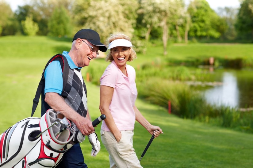 Cheerful mature couple walking on a golf course